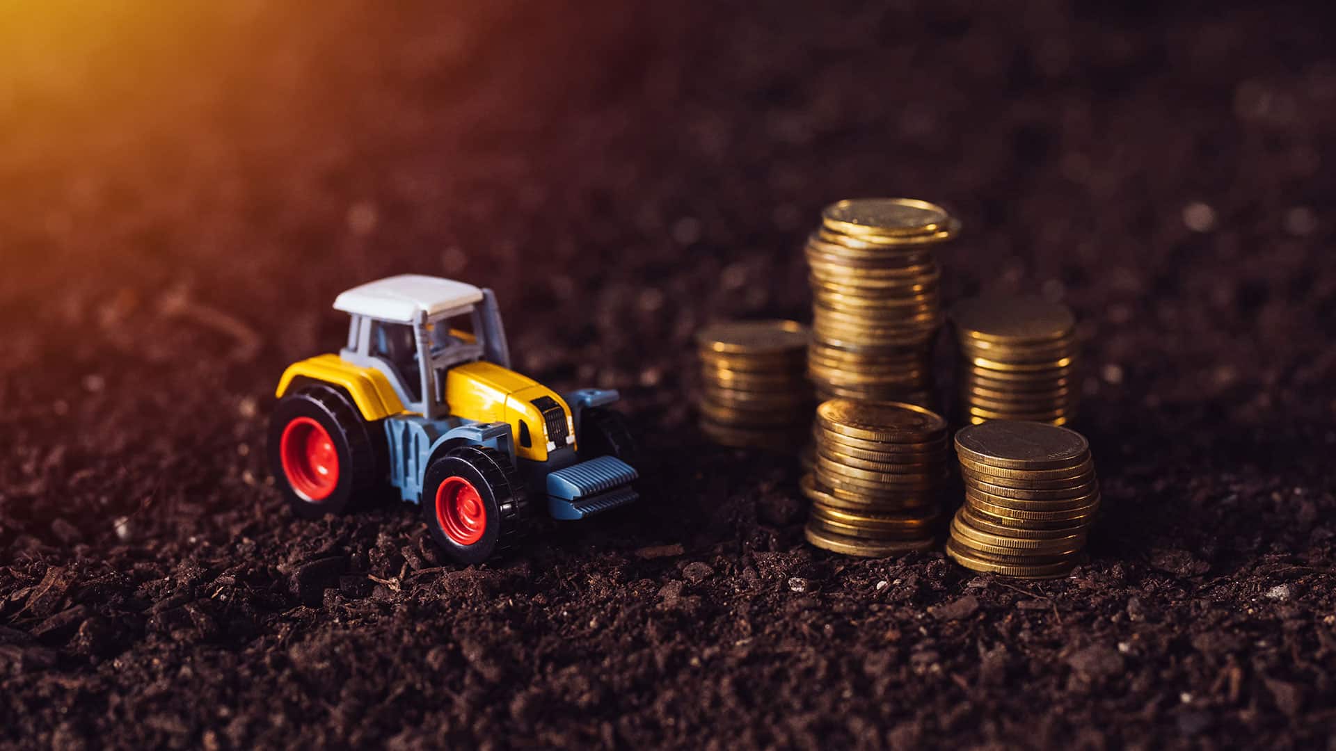 Modelltraktor og mynter som illustrerer kapitalbehov i landbruket